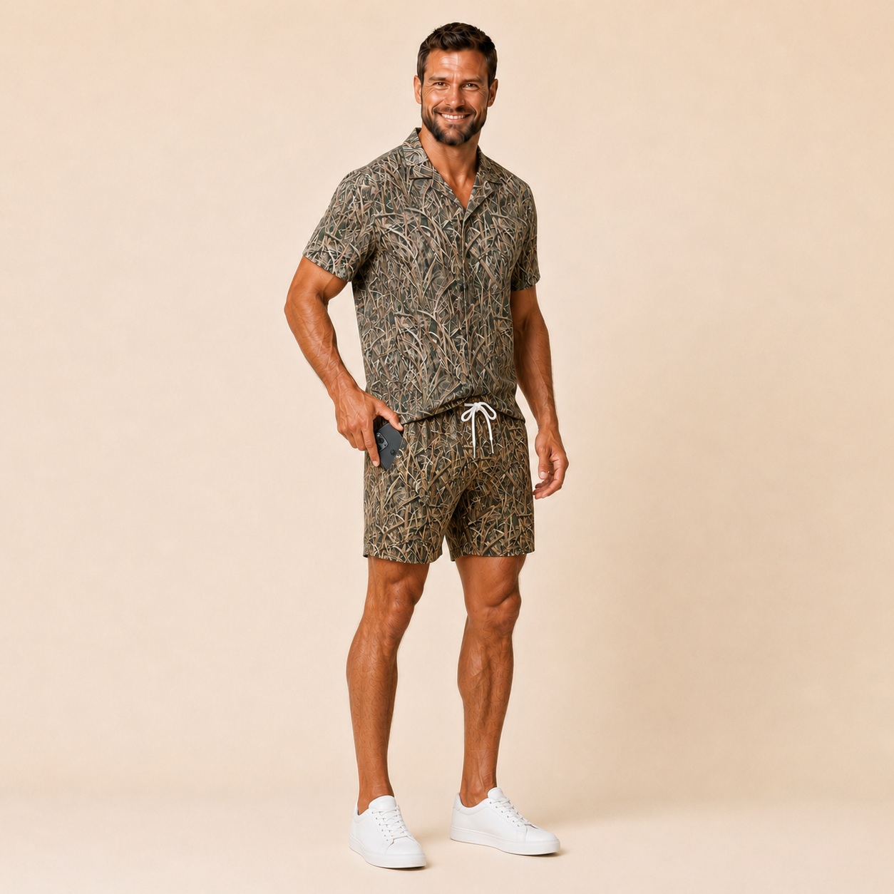 Man wearing Silpaz vintage duck camo shorts in Tan Grass Camo with a matching camp shirt, full length front view
