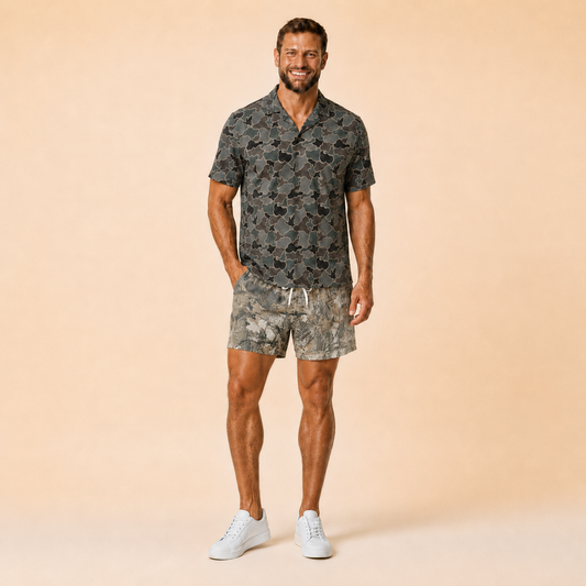 Man wearing Silpaz realistic camo mesh shorts in Tan Leaf Camo with a dark camp shirt, full length front view