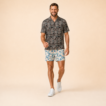 Man wearing Silpaz duck camo athletic shorts in cream blue camo, walking pose