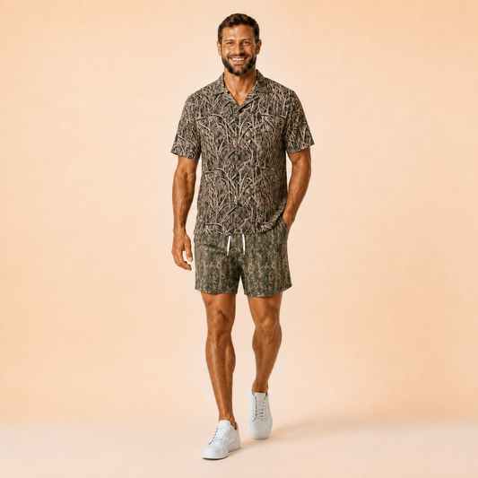 Man wearing Silpaz tree bark camo mesh shorts in Green Leaf Camo with a matching camp shirt, full length front view