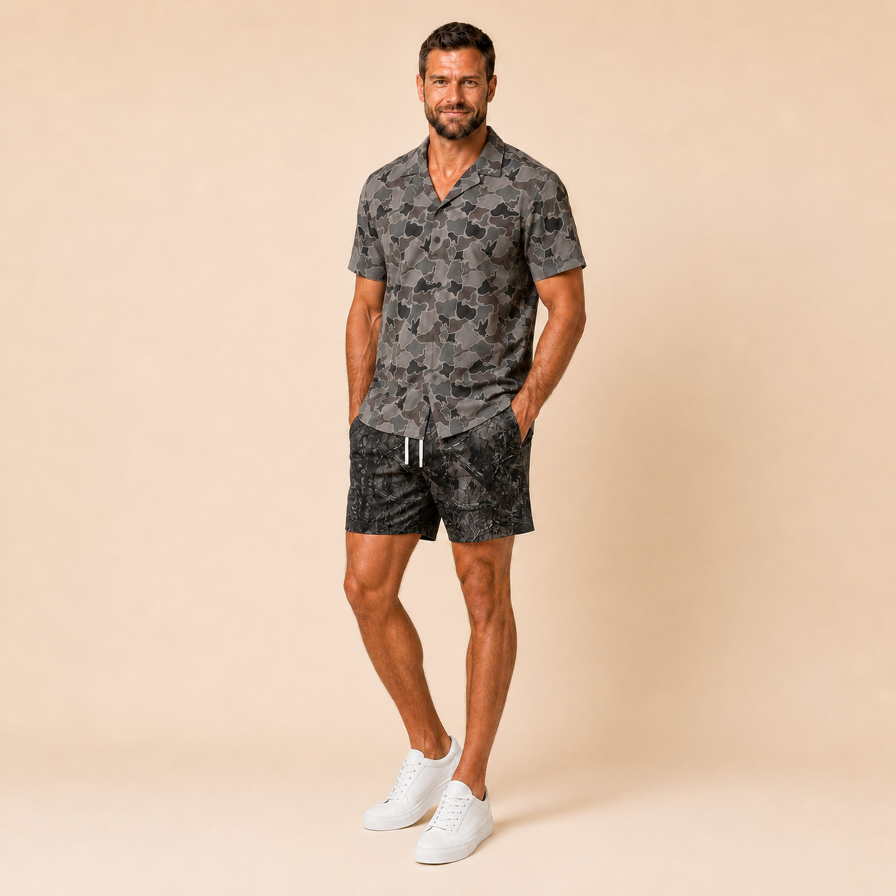 Man wearing Silpaz duck camo sport shorts in black camo, hand in pocket, full length view