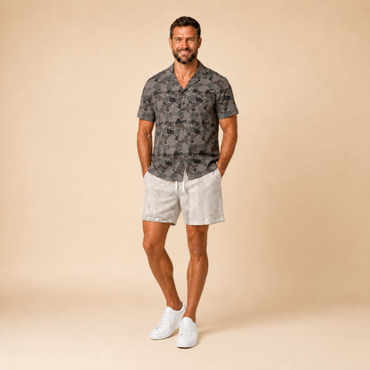 Man wearing Silpaz duck camo sport shorts in Tan Camo with a dark camp shirt, full length front view