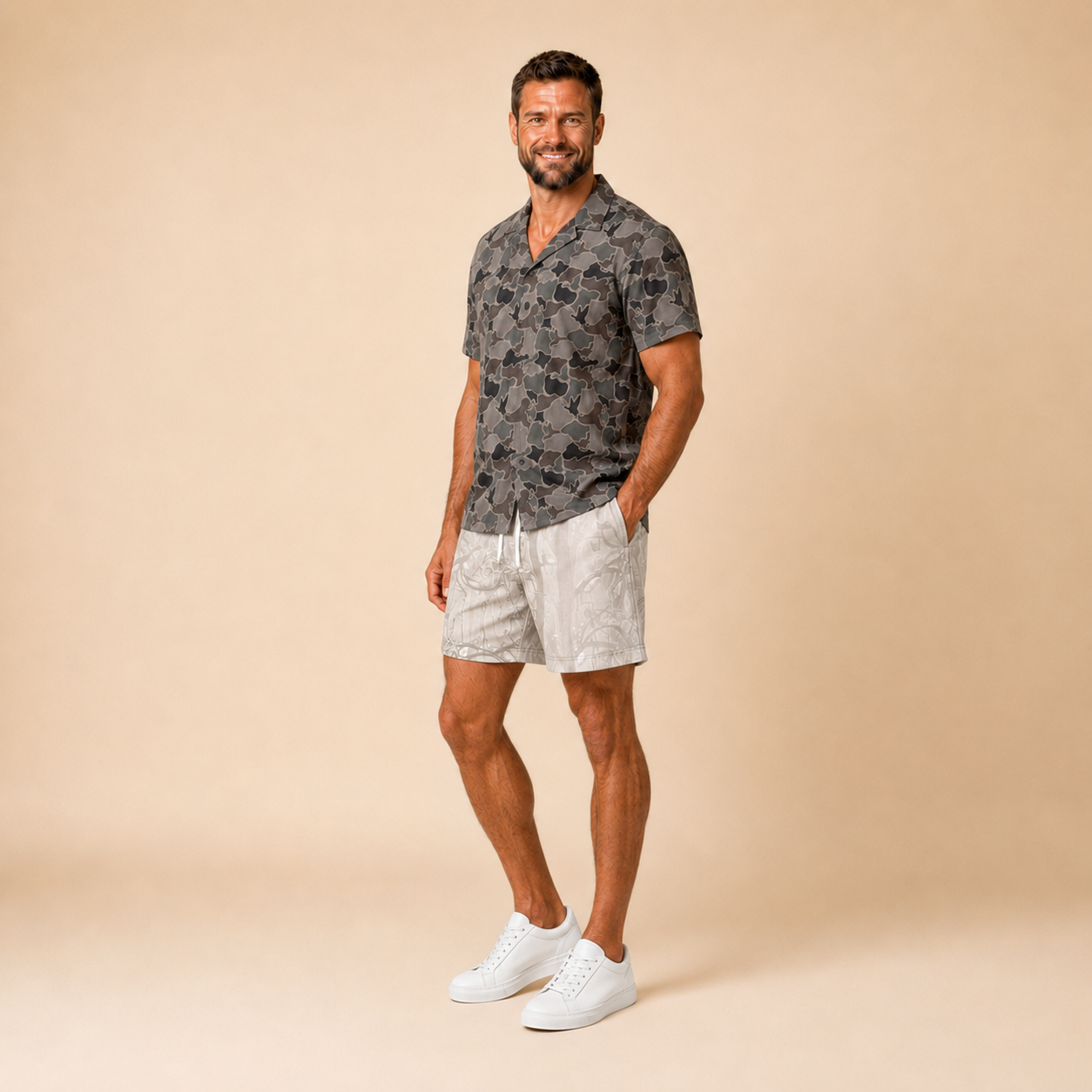 Man wearing Silpaz duck camo sport shorts in cream camo with a dark camp shirt, full length front view