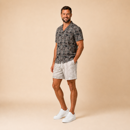 Man wearing Silpaz duck camo sport shorts in cream camo with a dark camp shirt, full length front view