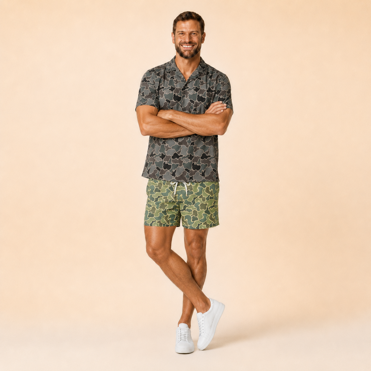 Man wearing Silpaz duck camo athletic shorts in sage green camo, arms crossed, full length view