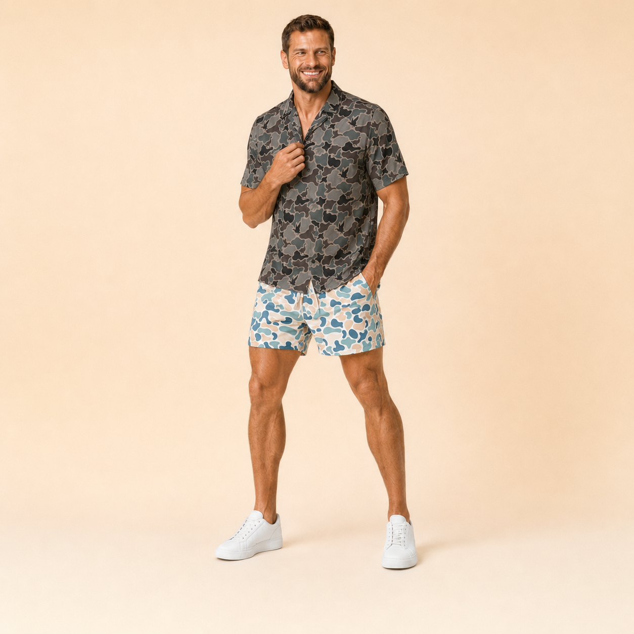 Man wearing Silpaz duck camo athletic shorts in light blue camo with a dark camp shirt, full length front view