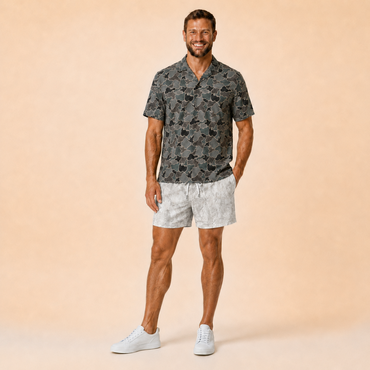 Man wearing Silpaz realistic camo mesh shorts in light snow camo with a dark camp shirt, standing pose