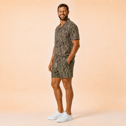 Man wearing Silpaz tree bark camo mesh shorts with a matching camp shirt, full length stepping pose