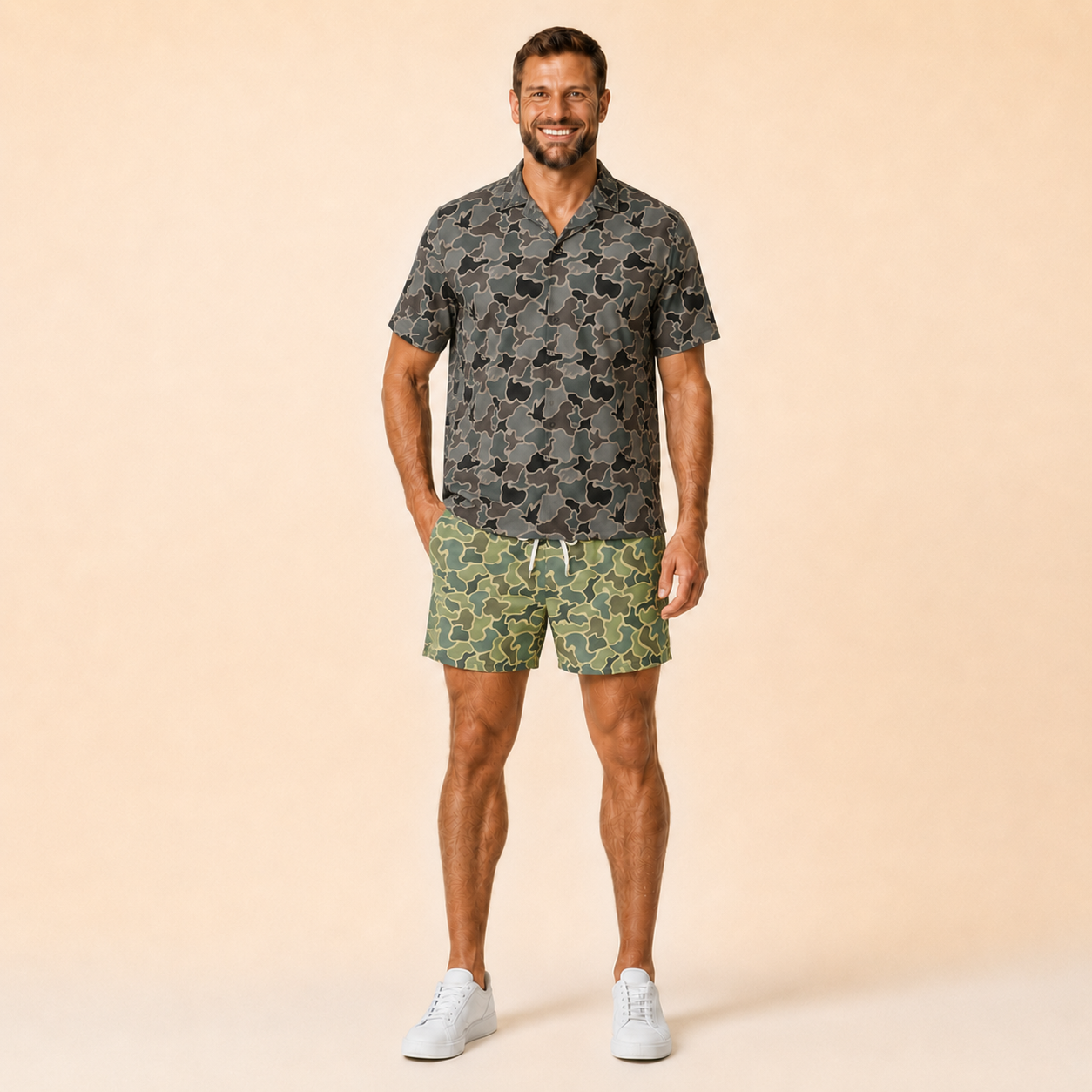 Man wearing Silpaz duck camo athletic shorts in sage green camo with a dark camp shirt, standing front view