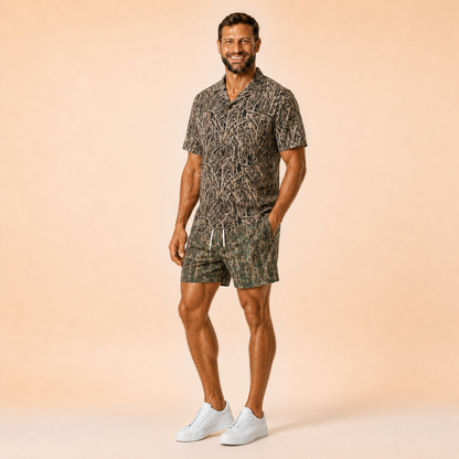Man wearing Silpaz tree bark camo mesh shorts with a matching camp shirt, standing front view